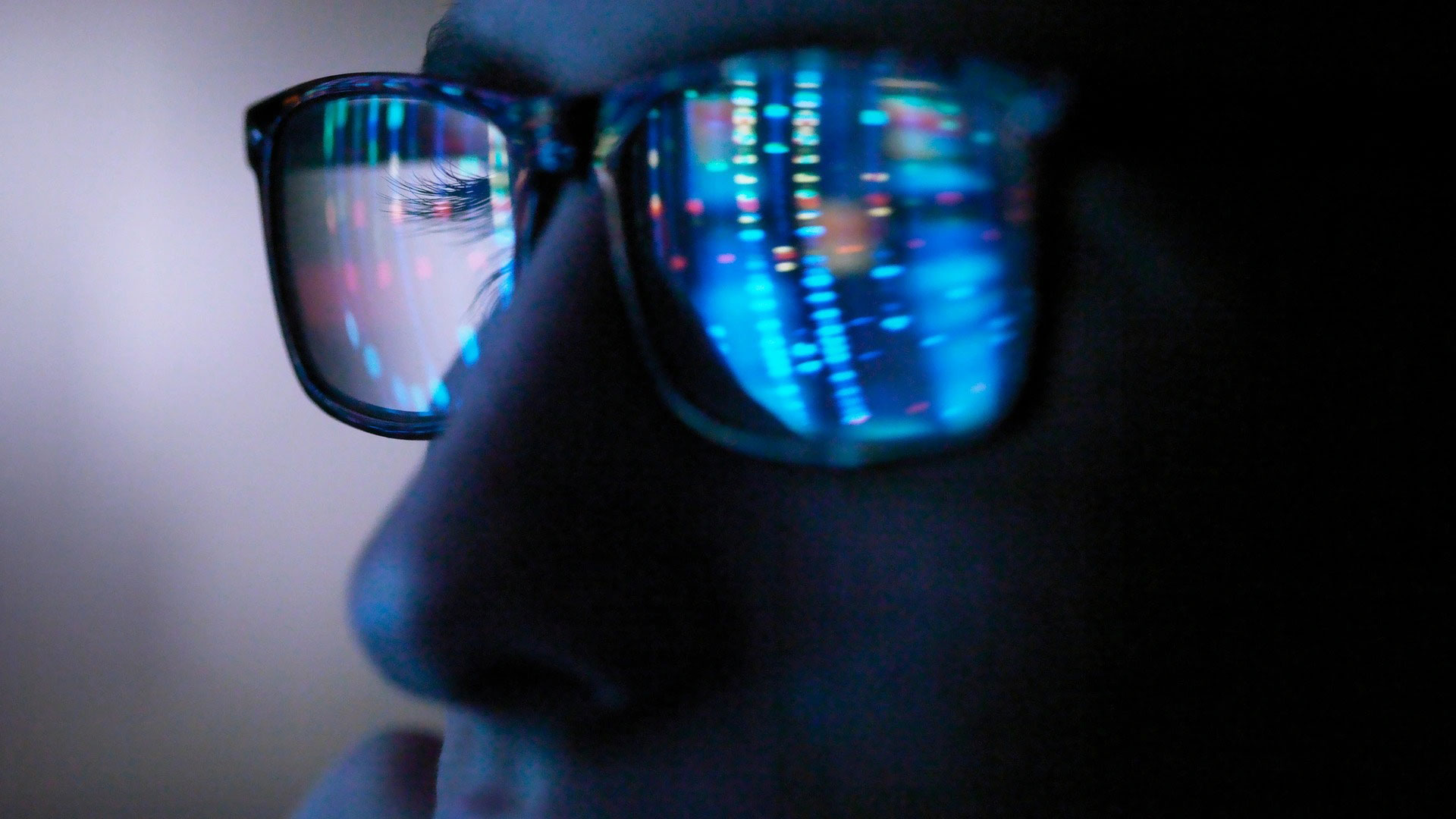 Close up of face with digital display reflected in their glasses